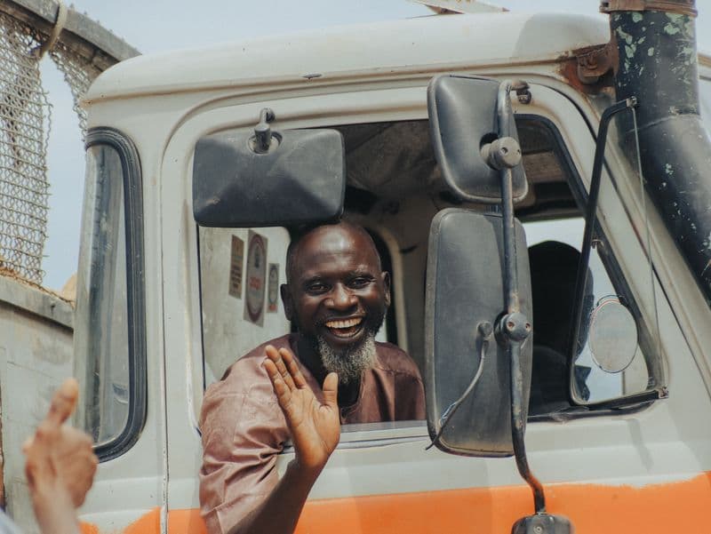 Experienced trucker smiling from the cab of his truck